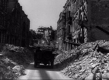Movie still from “A Foreign Affair” (1948), directed by Billy Wilder – An old truck driving down a road in a destroyed city; Wide shot, High angle