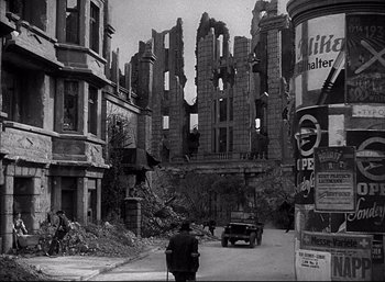 Movie still from “A Foreign Affair” (1948), directed by Billy Wilder – An old photo of a street with a car parked in front of a building; Wide shot, Low angle