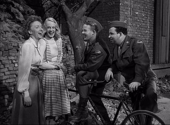 Movie still from “A Foreign Affair” (1948), directed by Billy Wilder – A group of people standing next to each other near a bicycle; Medium shot, Low angle