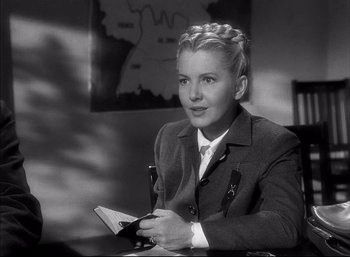 Movie still from “A Foreign Affair” (1948), directed by Billy Wilder – A woman sitting at a table holding a book; Close Up shot, Over the shoulder angle
