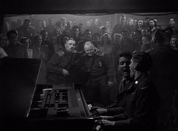 Movie still from “A Foreign Affair” (1948), directed by Billy Wilder – A group of men and women playing a piano; Wide shot, Low angle