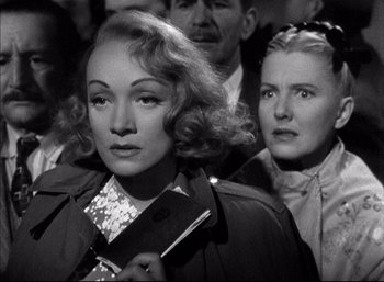 Movie still from “A Foreign Affair” (1948), directed by Billy Wilder – A woman holding a purse while standing next to another woman; Close Up shot, Over the shoulder angle