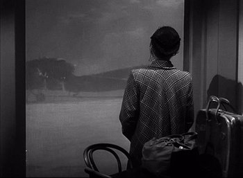 Movie still from “A Foreign Affair” (1948), directed by Billy Wilder – A woman standing in front of a window looking out; Medium shot, Over the shoulder angle