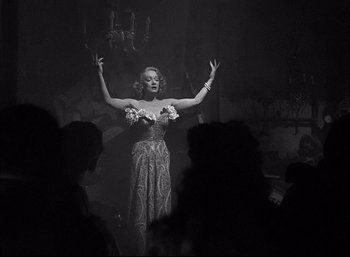Movie still from “A Foreign Affair” (1948), directed by Billy Wilder – A woman in an evening gown with her arms outstreched; Medium shot, Low angle