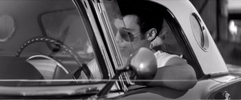 Movie still from “A Girl Walks Home Alone at Night” (2014), directed by Ana Lily Amirpour – A young man driving a car in a black and white photo; Medium shot, Over the shoulder angle