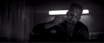 Movie still from “A Girl Walks Home Alone at Night” (2014), directed by Ana Lily Amirpour – A man is eating something while sitting in a room; Close Up shot, Low angle