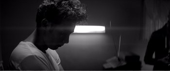 Movie still from “A Girl Walks Home Alone at Night” (2014), directed by Ana Lily Amirpour – A black - and - white photo of a man looking at a laptop; Close Up shot, Low angle