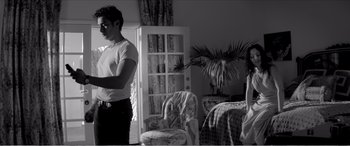 Movie still from “A Girl Walks Home Alone at Night” (2014), directed by Ana Lily Amirpour – A man standing in front of a door in a living room; Medium shot, Low angle