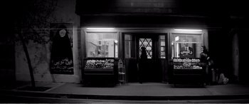 Movie still from “A Girl Walks Home Alone at Night” (2014), directed by Ana Lily Amirpour – A person standing in front of a store at night; Wide shot, Low angle