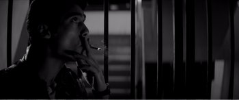 Movie still from “A Girl Walks Home Alone at Night” (2014), directed by Ana Lily Amirpour – A man is smoking a cigarette in a dark room; Close Up shot, Low angle