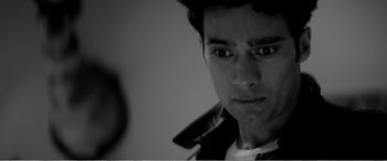 Movie still from “A Girl Walks Home Alone at Night” (2014), directed by Ana Lily Amirpour – A young man is looking into the camera; Close Up shot, Over the shoulder angle