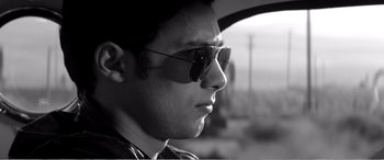 Movie still from “A Girl Walks Home Alone at Night” (2014), directed by Ana Lily Amirpour – Black and white photograph of a man wearing sunglasses; Close Up shot, Low angle