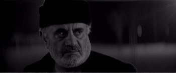 Movie still from “A Girl Walks Home Alone at Night” (2014), directed by Ana Lily Amirpour – An old man with a beard wearing a black hat; Close Up shot, Low angle