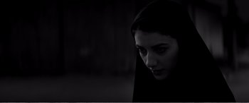 Movie still from “A Girl Walks Home Alone at Night” (2014), directed by Ana Lily Amirpour – A woman in a black robe is looking at the camera; Close Up shot, Low angle