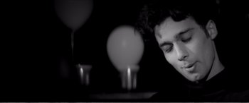Movie still from “A Girl Walks Home Alone at Night” (2014), directed by Ana Lily Amirpour – A man sitting in front of a lit candle in a room; Close Up shot, Low angle