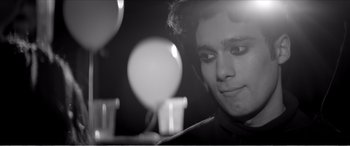 Movie still from “A Girl Walks Home Alone at Night” (2014), directed by Ana Lily Amirpour – A man looking at a light bulb in a dimly - lit room; Close Up shot, Low angle