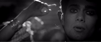 Movie still from “A Girl Walks Home Alone at Night” (2014), directed by Ana Lily Amirpour – A person with their hand up to their ear; Extreme Close Up shot, Low angle