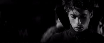 Movie still from “A Girl Walks Home Alone at Night” (2014), directed by Ana Lily Amirpour – A young man with curly hair is holding a cell phone; Close Up shot, Over the shoulder angle