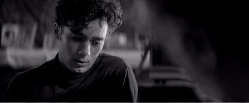 Movie still from “A Girl Walks Home Alone at Night” (2014), directed by Ana Lily Amirpour – Black and white photograph of a young man with curly hair; Close Up shot, Low angle