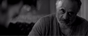 Movie still from “A Girl Walks Home Alone at Night” (2014), directed by Ana Lily Amirpour – An older man sitting in front of a window; Close Up shot, Over the shoulder angle