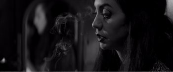 Movie still from “A Girl Walks Home Alone at Night” (2014), directed by Ana Lily Amirpour – A black - and - white photo of a woman smoking a cigarette; Close Up shot, Low angle