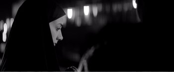 Movie still from “A Girl Walks Home Alone at Night” (2014), directed by Ana Lily Amirpour – A woman wearing a black headscarf looking at a cell phone; Close Up shot, Over the shoulder angle