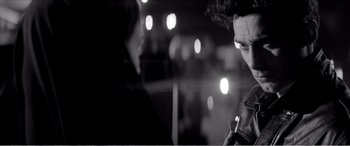 Movie still from “A Girl Walks Home Alone at Night” (2014), directed by Ana Lily Amirpour – A man holding a cell phone in front of lights; Close Up shot, Over the shoulder angle