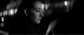 Movie still from “A Girl Walks Home Alone at Night” (2014), directed by Ana Lily Amirpour – A woman looking at her cell phone while sitting in a chair; Close Up shot, Low angle