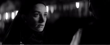 Movie still from “A Girl Walks Home Alone at Night” (2014), directed by Ana Lily Amirpour – A woman in a black shirt is looking at the camera; Close Up shot, Over the shoulder angle