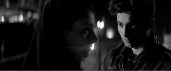 Movie still from “A Girl Walks Home Alone at Night” (2014), directed by Ana Lily Amirpour – A man and a woman face to face in a black - and - white photo; Close Up shot, Over the shoulder angle