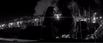 Movie still from “A Girl Walks Home Alone at Night” (2014), directed by Ana Lily Amirpour – A man and a woman standing next to each other in front of a building; Medium shot, Over the shoulder angle