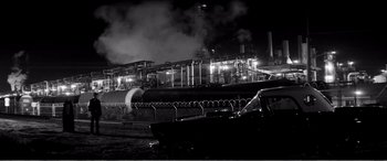 Movie still from “A Girl Walks Home Alone at Night” (2014), directed by Ana Lily Amirpour – A black and white photo of a factory at night; Extreme Wide shot, High angle