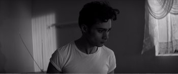 Movie still from “A Girl Walks Home Alone at Night” (2014), directed by Ana Lily Amirpour – Black and white photograph of a young man in a white shirt; Close Up shot, Low angle