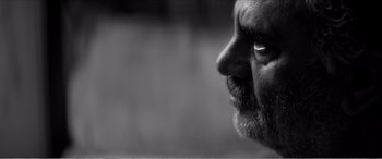 Movie still from “A Girl Walks Home Alone at Night” (2014), directed by Ana Lily Amirpour – A man with a beard looking to the side; Extreme Close Up shot, Low angle