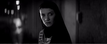 Movie still from “A Girl Walks Home Alone at Night” (2014), directed by Ana Lily Amirpour – A woman with a black veil on her head; Close Up shot, Low angle