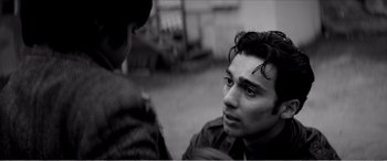 Movie still from “A Girl Walks Home Alone at Night” (2014), directed by Ana Lily Amirpour – A black - and - white photo of a man talking to another man; Close Up shot, Over the shoulder angle