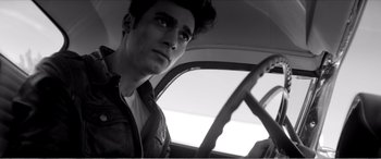 Movie still from “A Girl Walks Home Alone at Night” (2014), directed by Ana Lily Amirpour – A man sitting in the driver's seat of a car; Close Up shot, Low angle