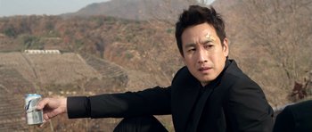A man sitting on top of a hill with his arm outstreched