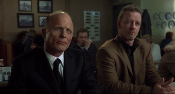 Movie still from “A History of Violence” (2005), directed by David Cronenberg – A group of men in suits and ties sitting next to each other in a room; Close Up shot, Low angle