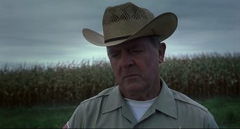 Movie still from “A History of Violence” (2005), directed by David Cronenberg – An older man wearing a cowboy hat in front of a corn field; Close Up shot, Low angle