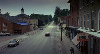 Movie still from “A History of Violence” (2005), directed by David Cronenberg – A car is driving down a street in a small town; Extreme Wide shot, High angle