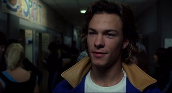 Movie still from “A History of Violence” (2005), directed by David Cronenberg – A man with long brown hair wearing a white shirt and a blue jacket; Close Up shot, Low angle