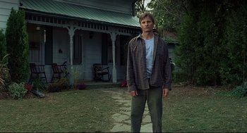 Movie still from “A History of Violence” (2005), directed by David Cronenberg – A man standing in front of a house; Wide shot, Low angle