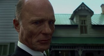 Movie still from “A History of Violence” (2005), directed by David Cronenberg – An old man with a bald head and a suit and tie; Close Up shot, Low angle