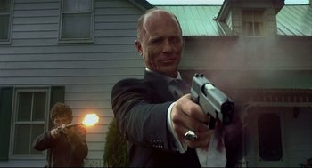 Movie still from “A History of Violence” (2005), directed by David Cronenberg – A man in a suit and tie holding a gun; Medium shot, Low angle