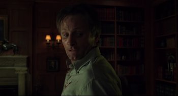 Movie still from “A History of Violence” (2005), directed by David Cronenberg – A man in a room with a book shelf in front of him; Medium shot, Low angle