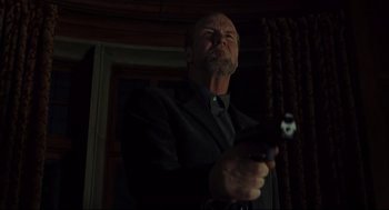 Movie still from “A History of Violence” (2005), directed by David Cronenberg – A man holding a gun while standing in front of a window; Medium shot, Low angle