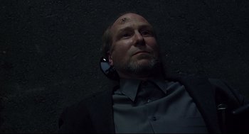 Movie still from “A History of Violence” (2005), directed by David Cronenberg – A man laying on the ground with a cell phone in his ear; Close Up shot, Overhead angle