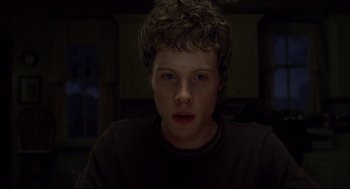 Movie still from “A History of Violence” (2005), directed by David Cronenberg – A young man with curly brown hair and blue eyes stares at the camera; Close Up shot, Low angle