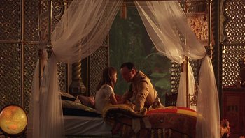Movie still from “A Little Princess” (1995), directed by Alfonso Cuarón – A man and a woman sitting on top of a four post bed; Wide shot, High angle